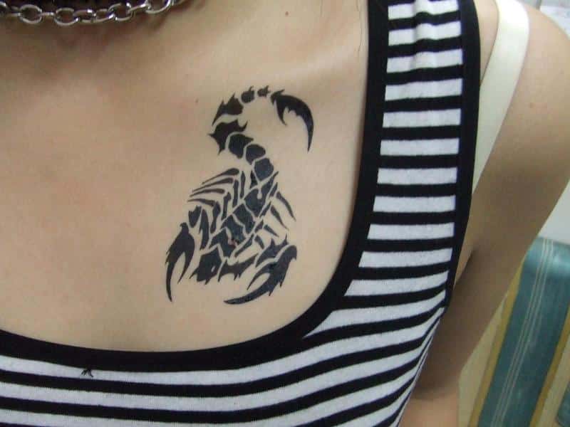 black scorpio tattoo on girl collarbone